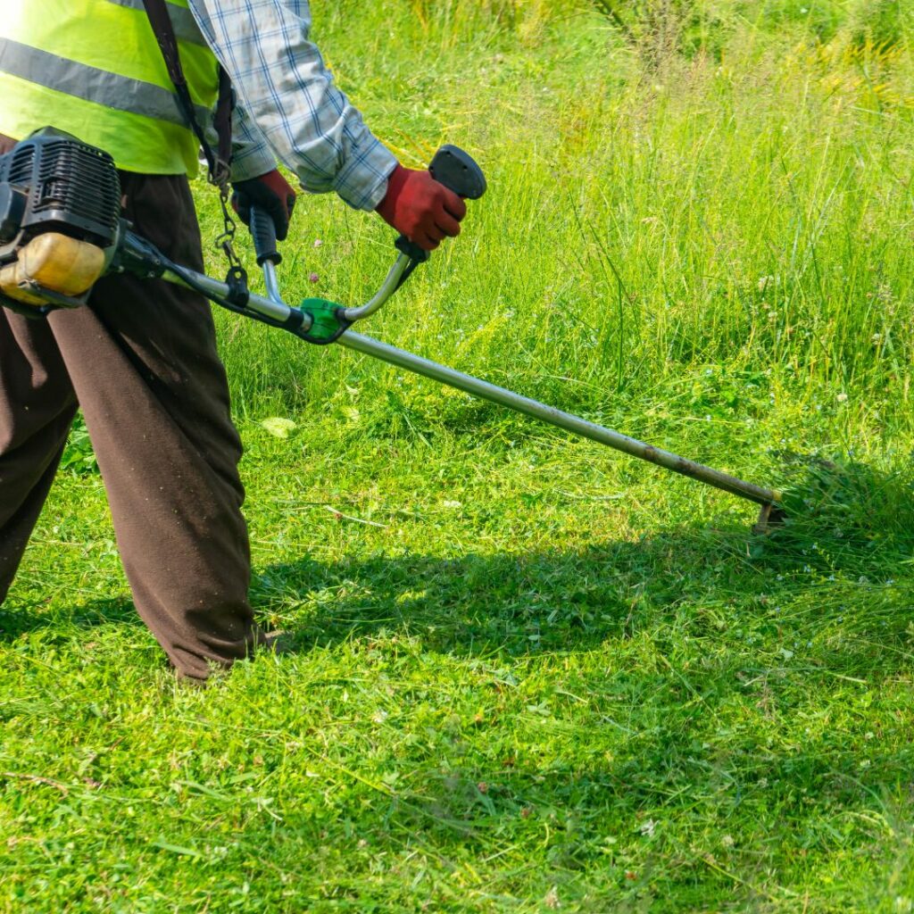 A man cutting a grass verge with a strimmer. Commercial grounds maintenance work in Rotherham.